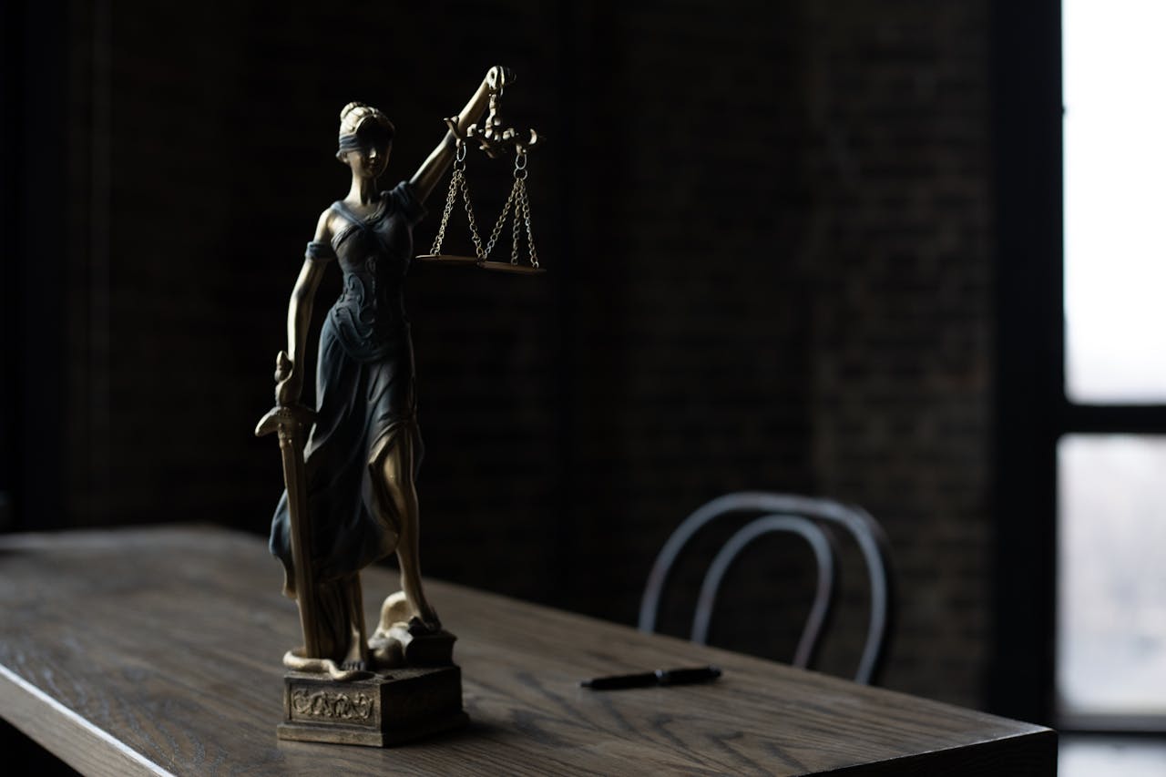 service-02 Lady Justice figurine on wooden table in dimly lit room symbolizes law and fairness.